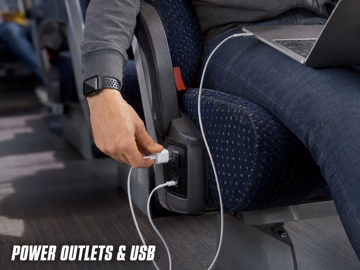 Charging cable plugged into an outlet beneath a charter bus seat