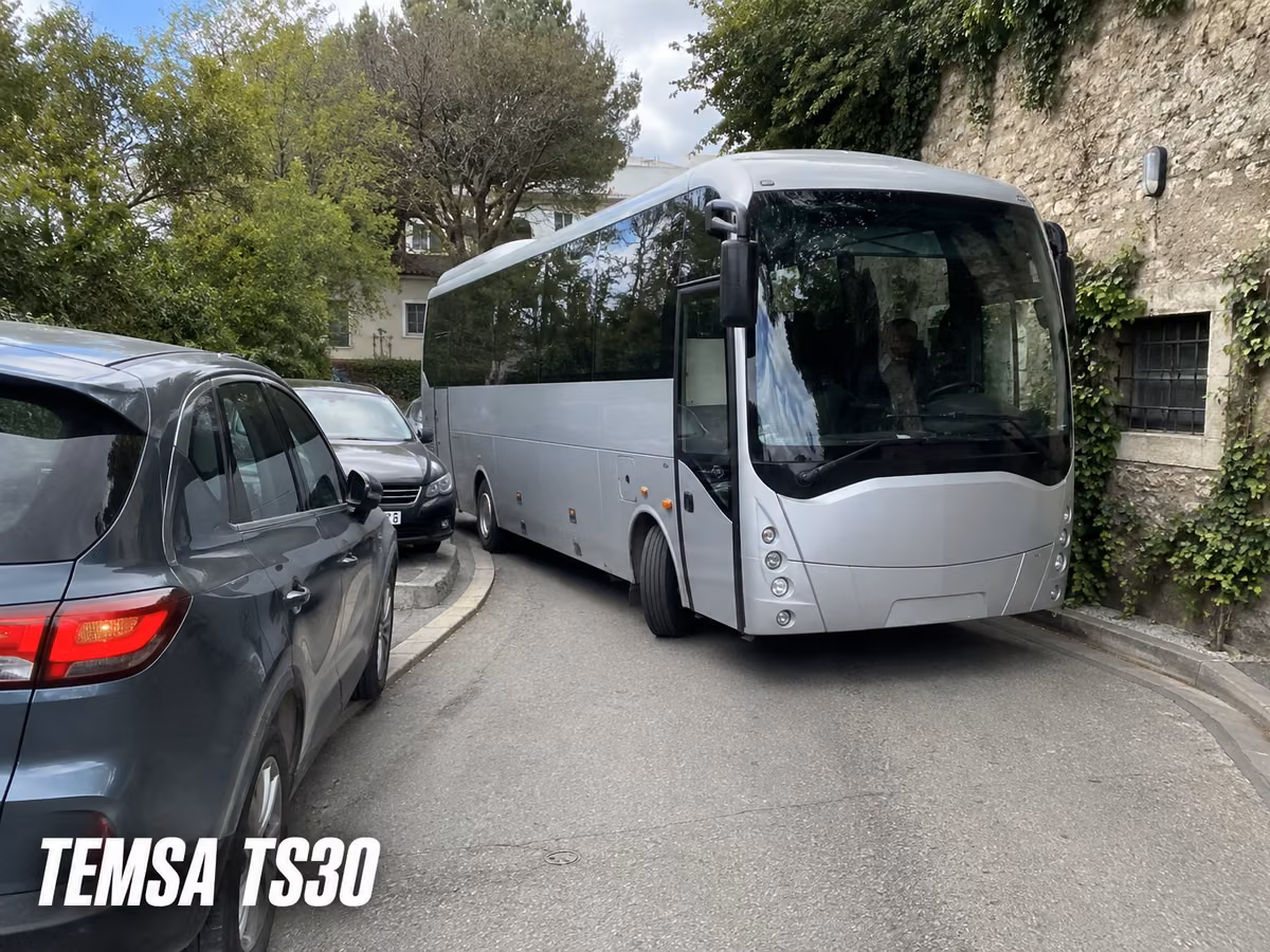 Temsa TS30 short coach parked on a narrow street beside cars