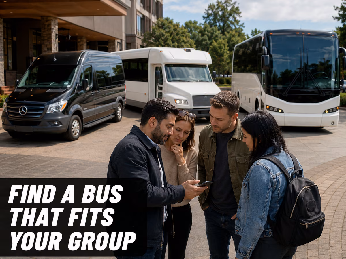 A small group standing between a black Sprinter van and a white coach, looking at a phone together.