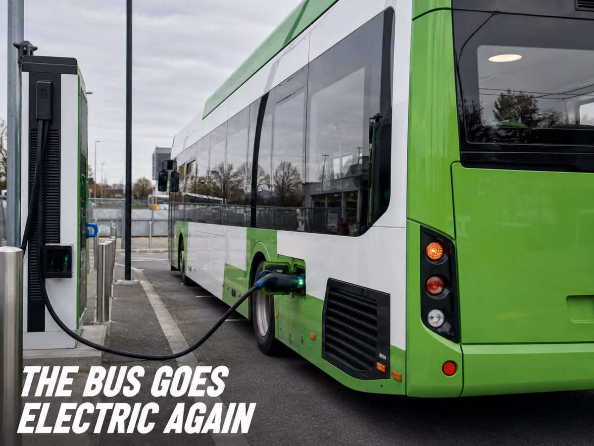 A green modern electric bus connected to a charging unit on a street