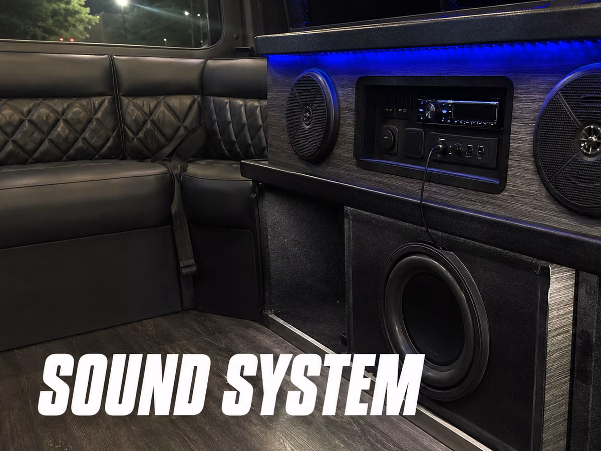 Close-up of a party bus audio system with a subwoofer and speakers set into a wood-trimmed cabinet