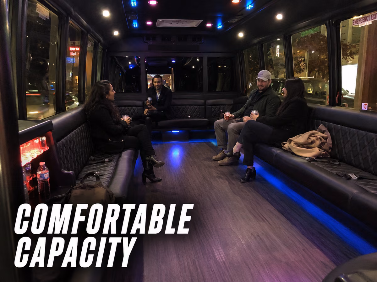 Passengers relaxing on perimeter benches inside a party bus lit with blue lighting