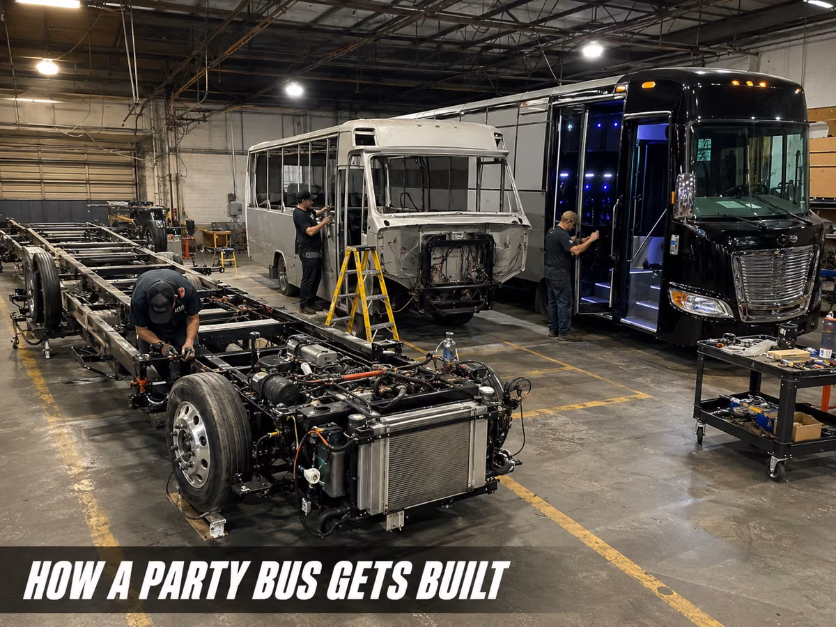 A bare party bus body shell under construction on its chassis inside a factory