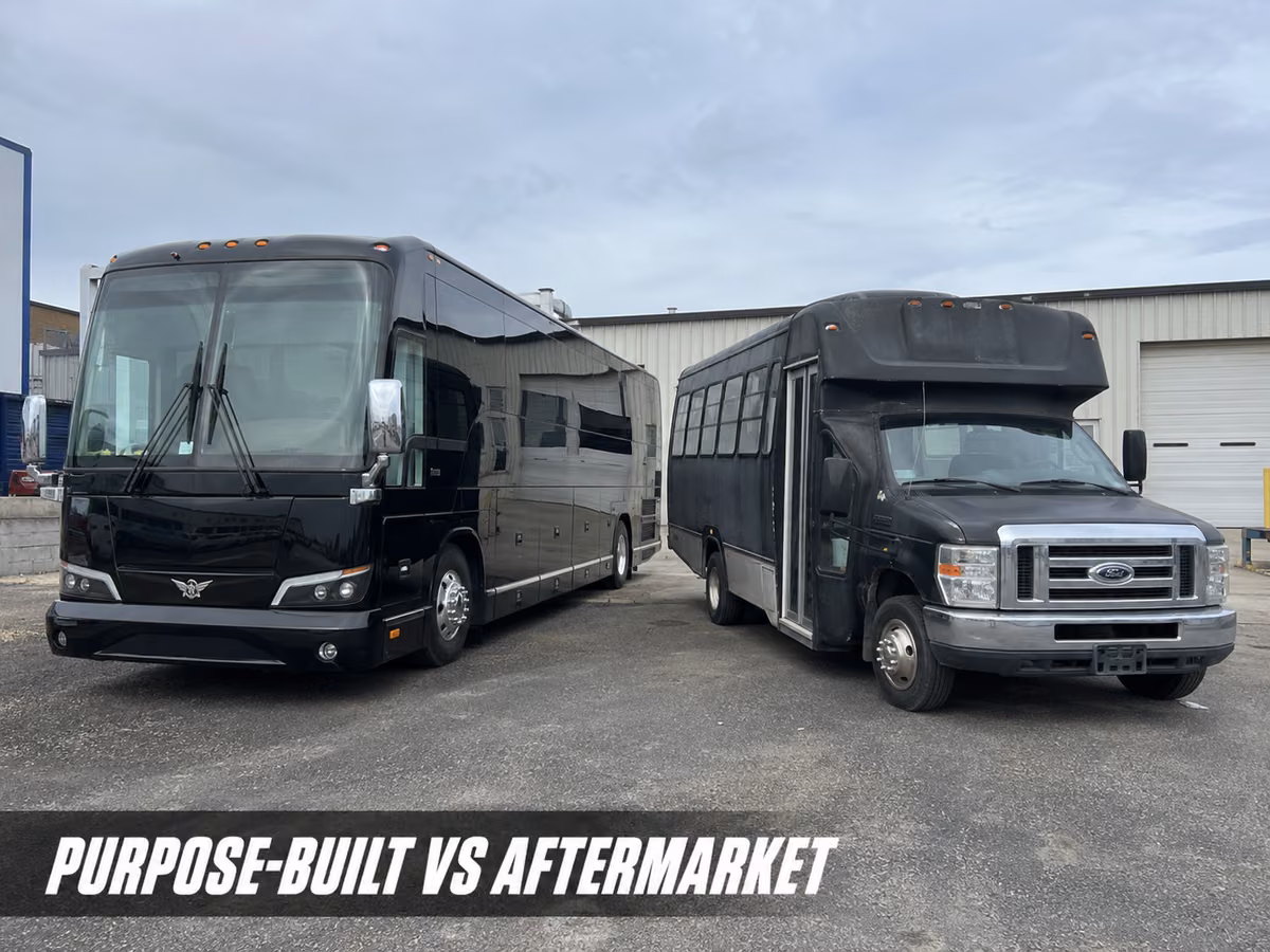 Two black party buses parked side by side outside a metal warehouse