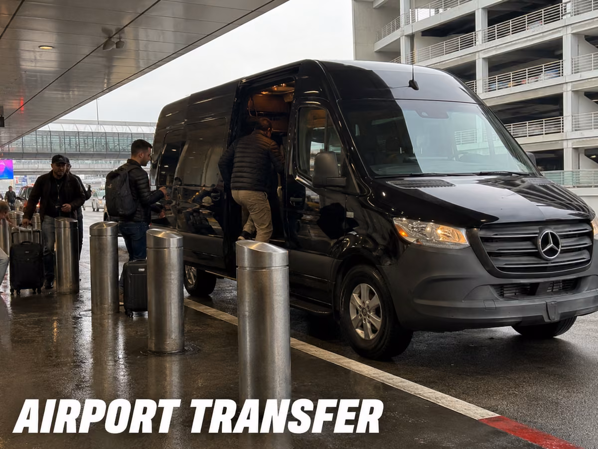 A black Mercedes-Benz Sprinter van parked at an airport curb while passengers load luggage on the sidewalk.